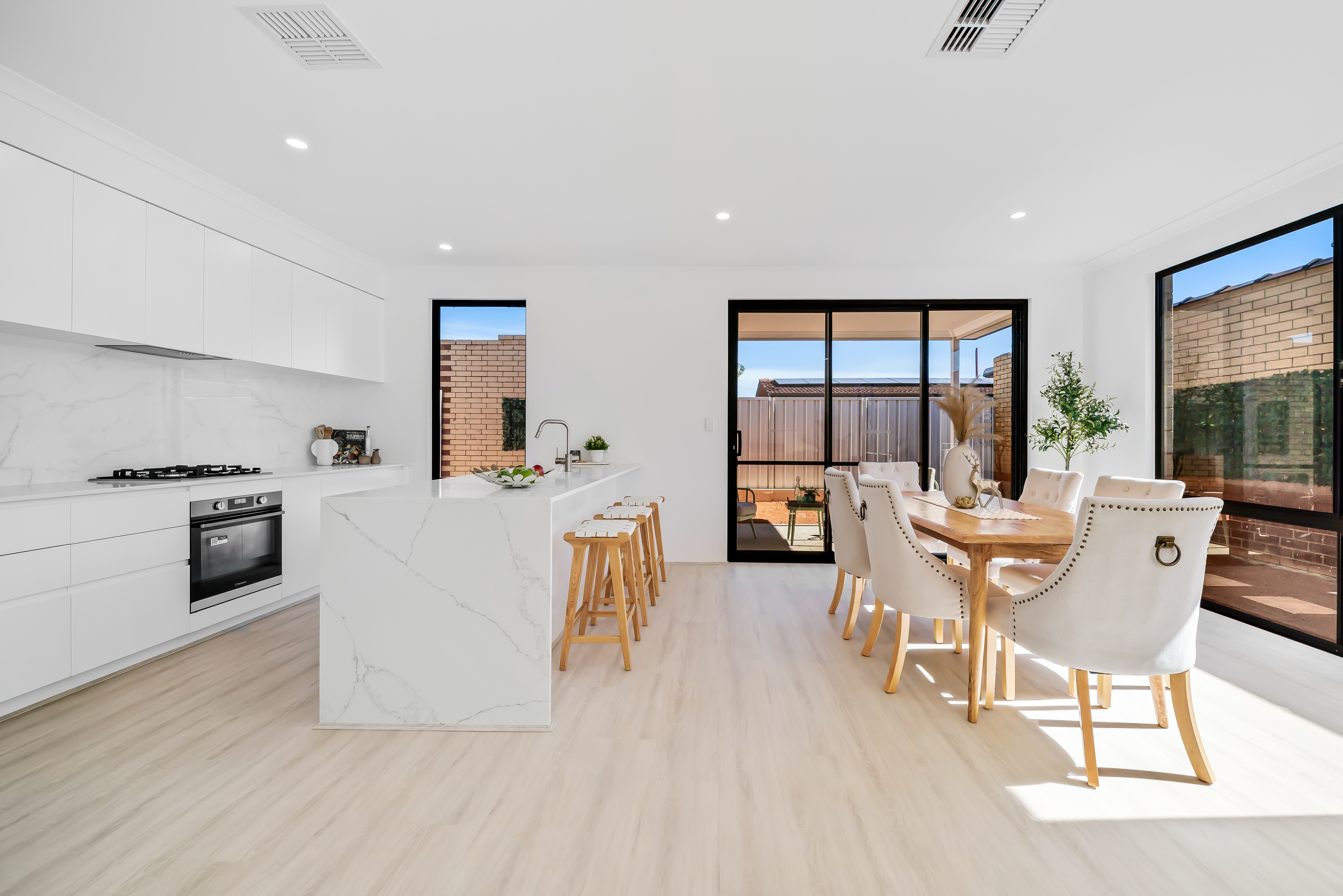 White kitchen and timber dining setting filled with natural light